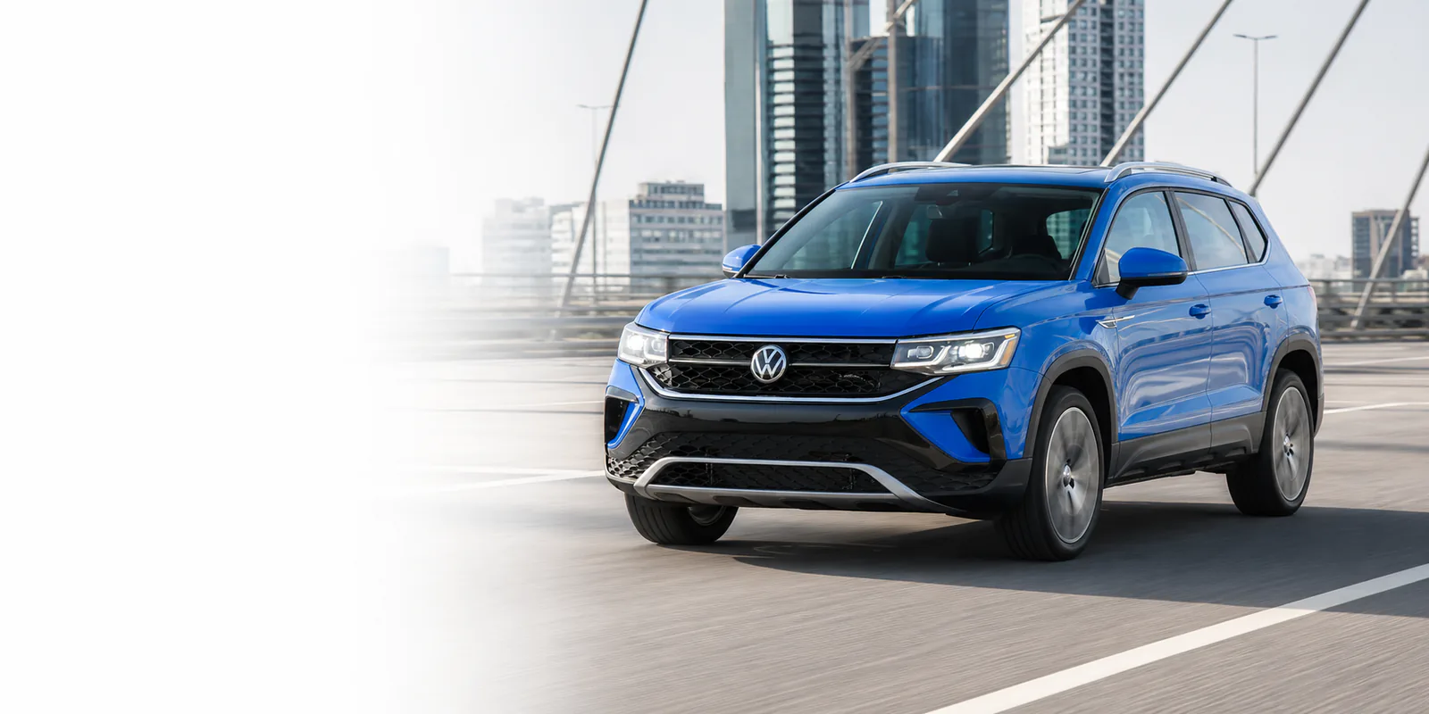 Синий Volkswagen Taos на современном городском мосту